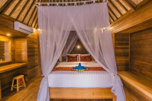 ein Schlafzimmer mit einem Himmelbett in einer Hütte in der Unterkunft Nerima Hut Lembongan in Nusa Lembongan