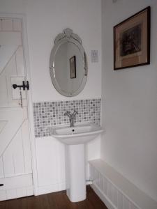 Baño blanco con lavabo y espejo en The Boat Inn, en Monmouth