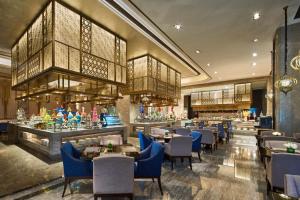 um restaurante com mesas e cadeiras e um bar em Wanda Vista Hotel Urumqi em Ürümqi