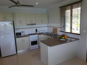 a kitchen with white appliances and a bowl of fruit on the counter at The Hub Vanuatu in Port Vila