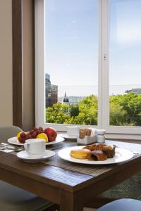 a table with plates of food on a table with a window at Riu Plaza España in Madrid