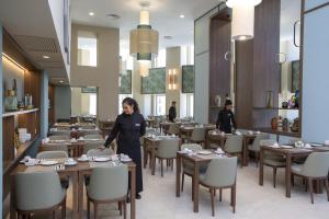 a woman standing in a dining room with tables and chairs at Riu Plaza España in Madrid