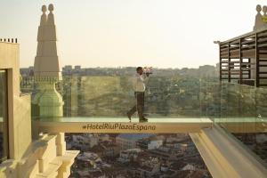 a man taking a picture of a city from the top of a building at Riu Plaza España in Madrid