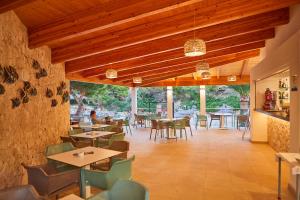 un restaurante con techos de madera, mesas y sillas en Hotel Rocamarina - Adults Only, en Cala d´Or