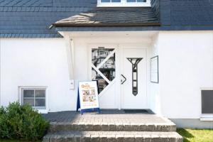 a white house with a sign in front of the door at Ferienwohnung Quick in Winterberg
