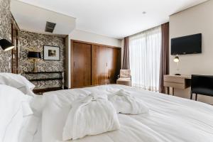 Una habitación de hotel con una cama blanca con toallas. en Hotel Villa Batalha, en Batalha