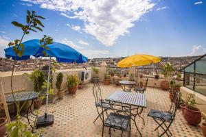 um pátio com cadeiras, mesas e guarda-sóis no telhado em Riad Zina Fes - Elegance in the Heart of Fes em Fez