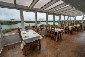 uma sala de jantar com mesas, cadeiras e janelas em Dimmuborgir Guesthouse em Myvatn