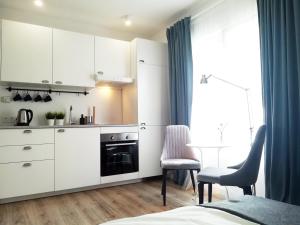 Una cocina con gabinetes blancos y una mesa y sillas. en Apartamenty Maki, en Gdansk