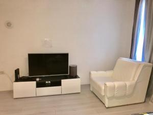 ein Wohnzimmer mit einem Flachbild-TV und einem weißen Stuhl in der Unterkunft Colors Apartment Sarajevo in Sarajevo