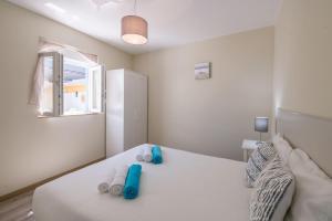 ein Schlafzimmer mit einem weißen Bett mit blauen Schuhen darauf in der Unterkunft LovelyStay - Sweet Escape II - Backyard in Quarteira