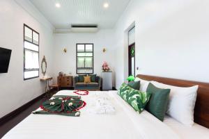 a bedroom with a large white bed with green pillows at Sound Gallery House - SHA Plus in Phuket