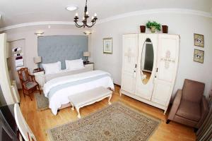 a bedroom with a large white bed and a chair at Oleander Guest House in Kimberley