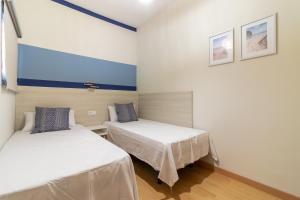 2 camas en una habitación con paredes blancas en Flatguest Agaete Blue, en Agaete