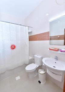 a white bathroom with a toilet and a sink at Al Bahjah Hotel in Seeb