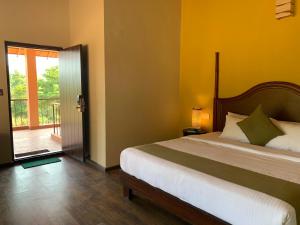 Schlafzimmer mit einem Bett und einer Tür zu einem Balkon in der Unterkunft Machaan Plantation Resort, Sakleshpur in Sakleshpur