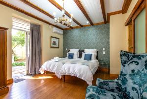ein Schlafzimmer mit einem großen Bett und einem Stuhl in der Unterkunft Evergreen Manor and Spa in Stellenbosch