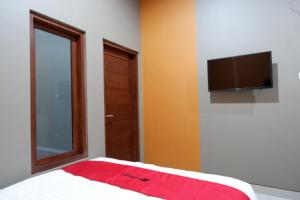 a bedroom with a bed with a television on the wall at RedDoorz Syariah near Stasiun Tegal in Tegal +11 photos