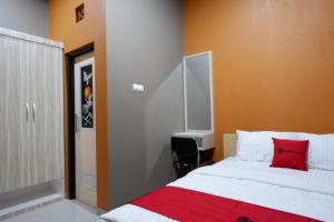 RedDoorz Syariah near Stasiun Tegal في تيغال: غرفة نوم بسرير ومخدة حمراء