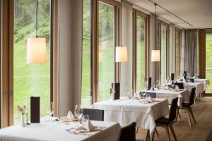 uma fila de mesas num restaurante com janelas em Tonzhaus Hotel em Senales