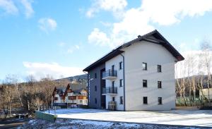 a white building with a black roof at Apartamenty EverySky - Wilcza 3F-1 in Karpacz