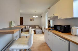 a kitchen and living room with white cabinets and a microwave at Apartamenty EverySky - Wilcza 3F-1 in Karpacz