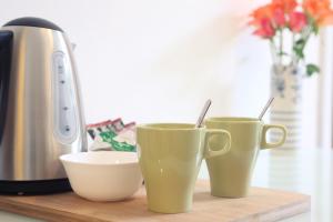 three green coffee cups sitting on a wooden cutting board at Southville Guest House in Bristol