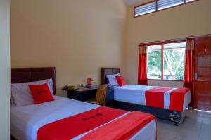 um quarto com 2 camas, uma secretária e uma janela em RedDoorz Syariah near Alun Alun Purwokerto em Purwokerto