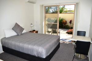 1 dormitorio con cama, escritorio y ventana en Redland Bay Motel, en Redland Bay