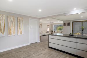 Una cocina con gabinetes blancos y una sala de estar. en East Coast Hideaway Beach Retreat, en Orford