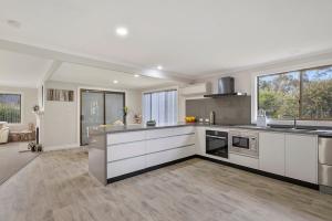 a large kitchen with white cabinets and a large window at East Coast Hideaway Beach Retreat in Orford