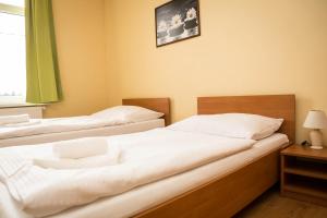 two beds in a room with white sheets at Penzion Burra in Vrútky