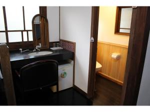 W łazience znajduje się umywalka, lustro i krzesło. w obiekcie Kotohira Guest House en w mieście Hita