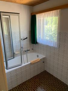 a bathroom with a shower and a tub with a window at Hotel Adler in Saas-Grund