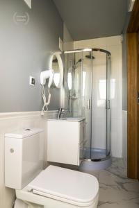 a white bathroom with a shower and a toilet at Hotel Warmia Spa in Braniewo