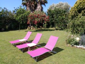 four pink lawn chairs sitting in the grass at Sous le mûrier in Six-Fours-les-Plages