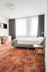 1 dormitorio con 1 cama y 1 silla en Hotel Warmia Spa, en Braniewo