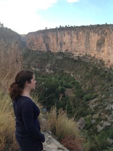 Eine Frau, die auf einer Klippe steht und auf einen Canyon schaut. in der Unterkunft Apartamentos La Muela - Chulilla in Chulilla