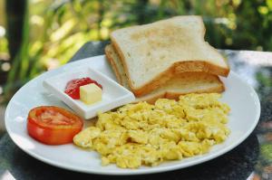 a plate of eggs and toast with a tomato and butter at Bokre Angkor Hostel in Siem Reap