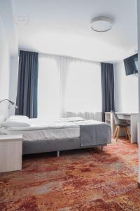 a bedroom with a bed and a desk and windows at Hotel Warmia Spa in Braniewo +17 photos