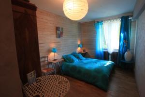 een slaapkamer met een blauw bed en een raam bij Le Mesnil in Dancé