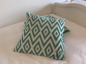 a green and white pillow on a bed at AVLiving City ROOM Basel in Basel