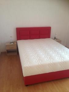 a bed with a red headboard in a bedroom at Apartments Ribić in Umag