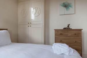 a bedroom with a white bed and a wooden dresser at Falcon House By RentMyHouse in Hereford