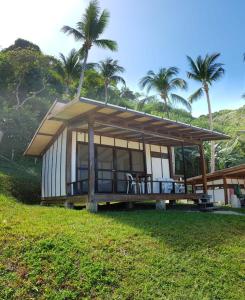 a small house with a roof on a grass field at Duli Beach Resort in El Nido