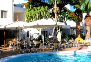 una piscina con sedie, tavoli e ombrelloni accanto a un hotel di Apartamentos Tamarindos a Puerto del Carmen