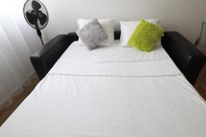 Cama negra con sábanas blancas y almohadas verdes en Studio scandinaves - Disneyland Paris en Serris
