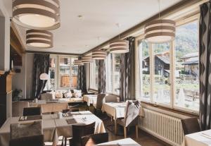ジナルにあるHôtel Le Besso - Swiss Romantic Lodge Zinalのテーブルと椅子、窓のあるレストラン