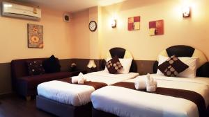バンコクにあるBaik Suiteのベッド2台とソファが備わるホテルルームです。