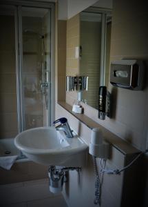 ein Badezimmer mit einem Waschbecken und einem Telefon an der Wand in der Unterkunft Hotel Gasthaus Weisser Mönch in Blankenburg